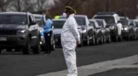 A healthcare worker watches over the line of people waiting to be tested for COVID-19 at the state's first drive-up testing center in Denver. (Michael Ciaglo/Getty Images)