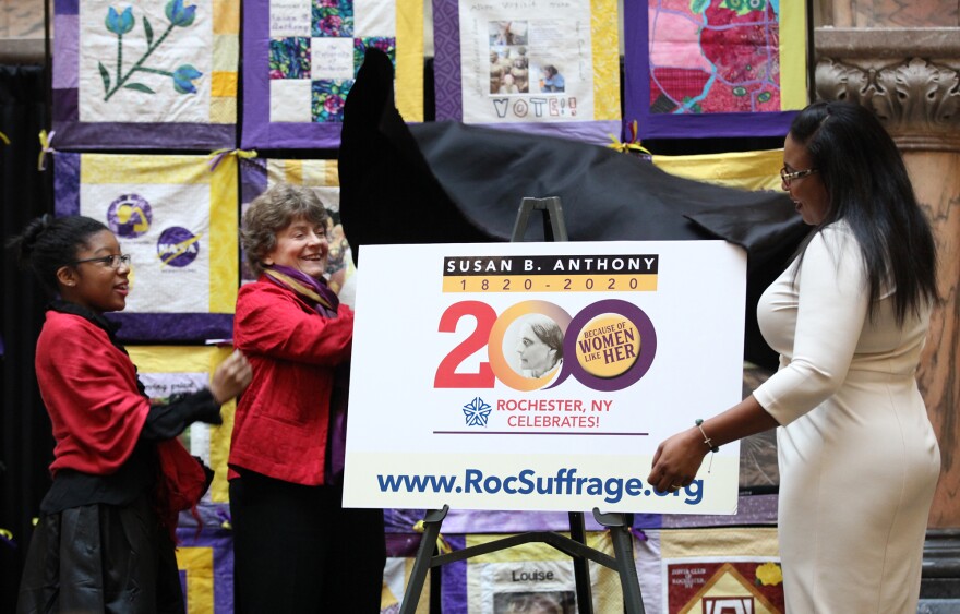 Mariedeliz Bain, Deborah Hughes, and Mayor Lovely Warren unveil the new logo commemorating Susan B. Anthony's 200th birthday.