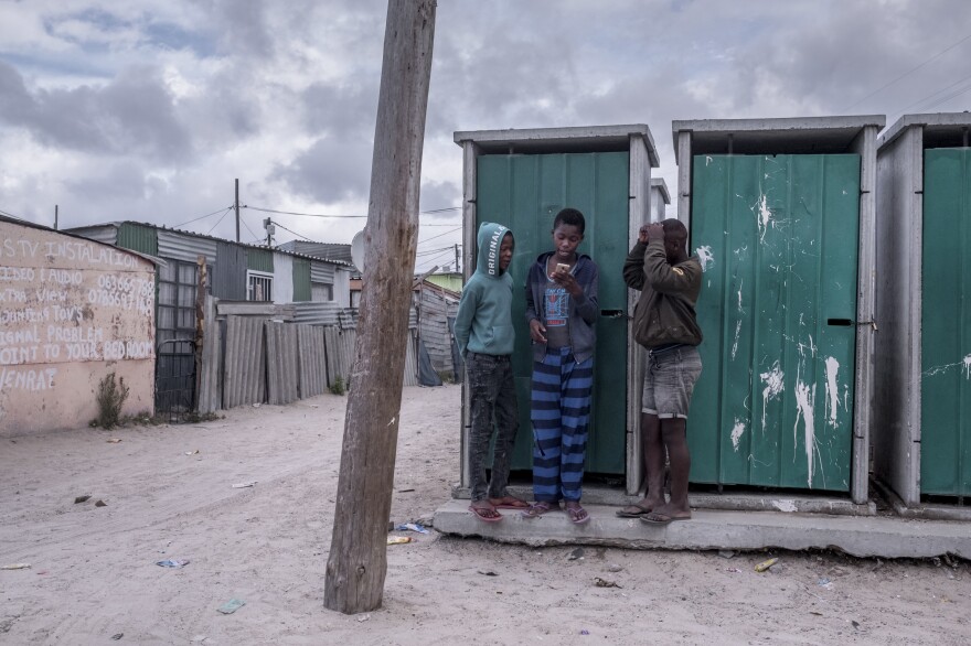 Boys gather at the communal toilets to get a cellphone signal in the township of Khayelitsha, Cape Town.