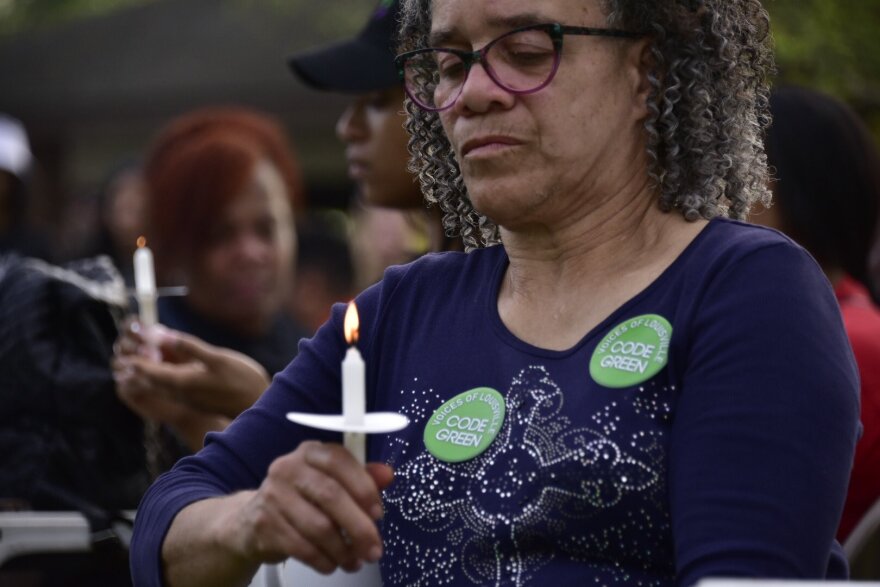 A woman holds a candle at a community event at Chickasaw Park in 2023.