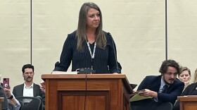 A woman in a navy blue top stands at a podium