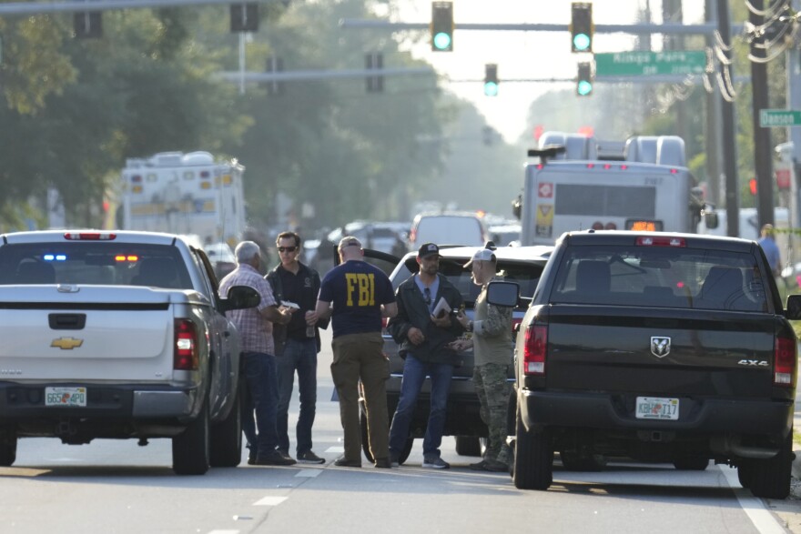 Law enforcement officials gather on the road to investigate the scene of a mass shooting.