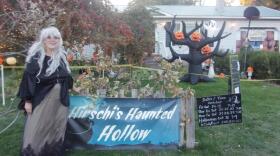 A woman in a witch's costume standing in her front yard.