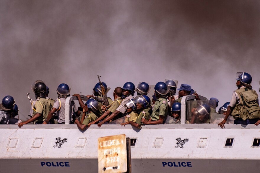 A police truck drives past a thick cloud of smoke as protesters burn tires in Bulawayo, Zimbabwe, during a tense, three-day nationwide protest against a fuel price hike in January.