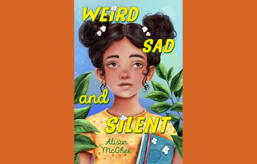 Cover of "Weird Sad and Silent" by Alison McGhee; colorful illustration of a girl in a yellow-orange floral shirt, holding a book and standing between two green plants