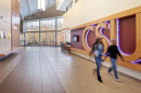 Two students walk past the letters C S U which are on the wall in a university building. 