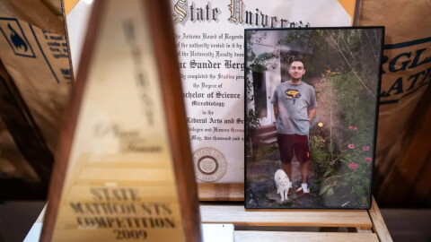 A photo of Isaac Berger with his cat, Frownie, is propped up in his bedroom near his college diploma and a state math competition trophy. A mathematical formula found by police on his computer seemed to calculate how many pills Isaac could take each day without dying.