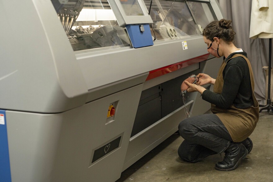 Myrrhia Resneck, in front of Bilio's flat-bed knitting machine, engineers mask prototypes using different techniques and yarn colors.