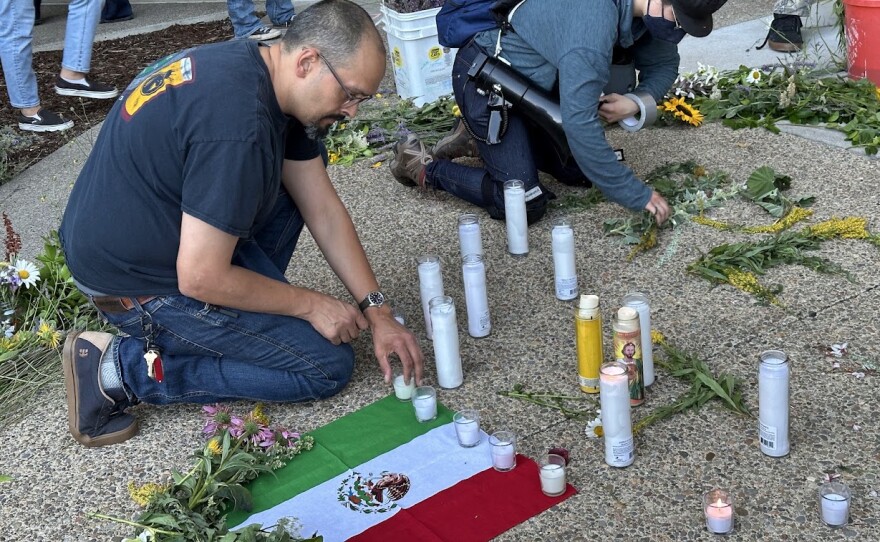 People laying candles across small Mexican flag. 