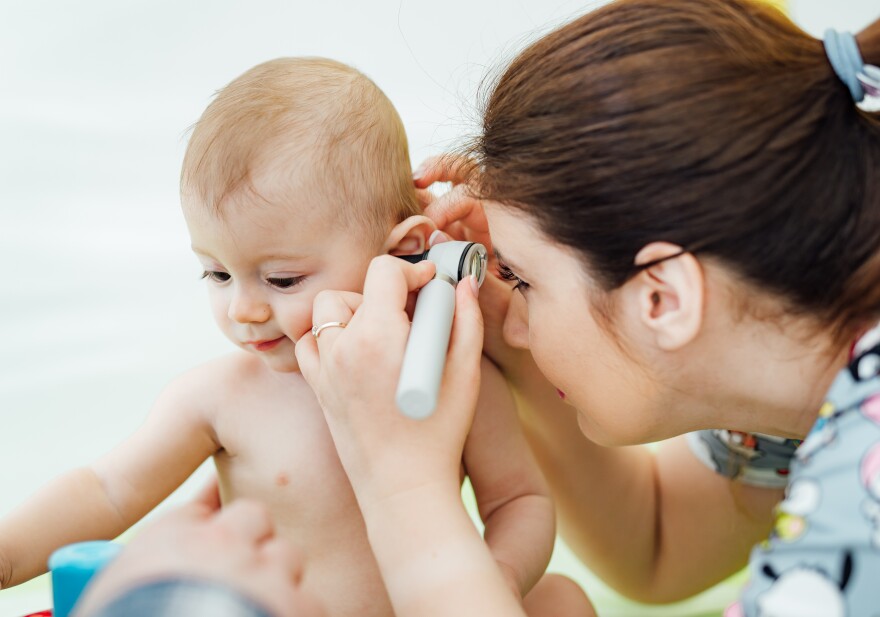Woman pediatrician is examining little baby in clinic.