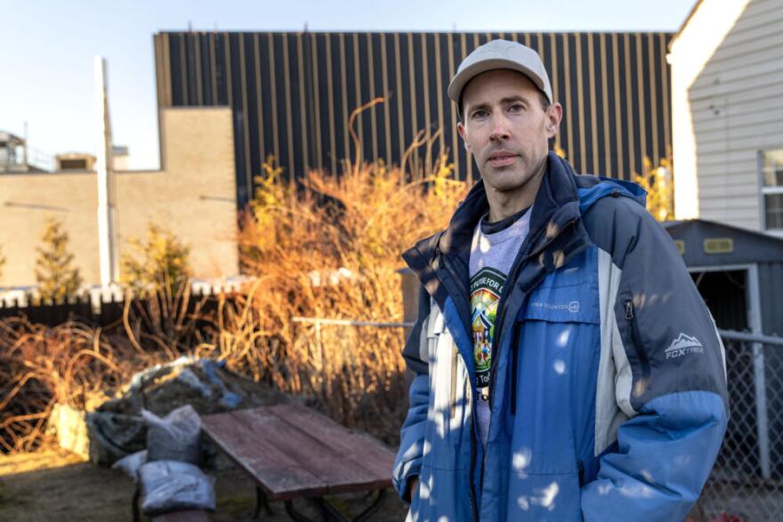 Jake Fortes stands in his yard with the Markley Lowell datacenter behind him. (Robin Lubbock/WBUR)