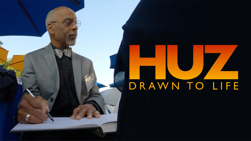 Ron Husband sits at a table to draw.