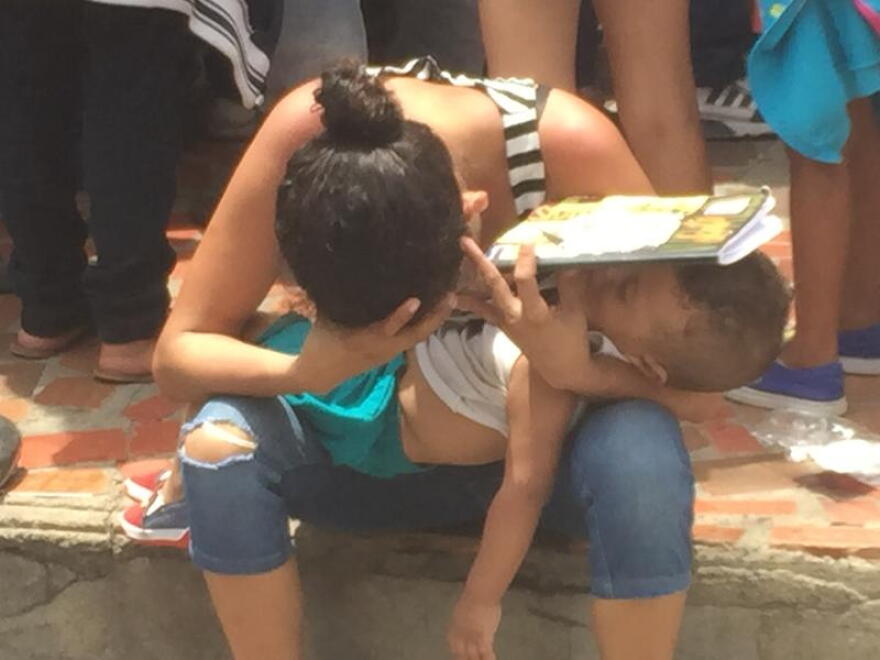 WORST HUMANITARIAN CRISIS: An exhausted Venezuelan refugee tries to give her toddler son shade while waiting for food stamps in Cucuta, Colombia, this year.