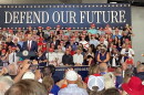 Man speaks at podium in front of a crowd