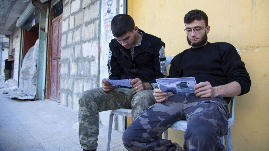 Opposition fighters in Aleppo look at fliers reportedly distributed by the Syrian government. The fliers encourage rebels to leave the eastern parts of the city. The Syrian army and its Russian ally have declared a "humanitarian pause," but there were few signs rebels or civilians were leaving.