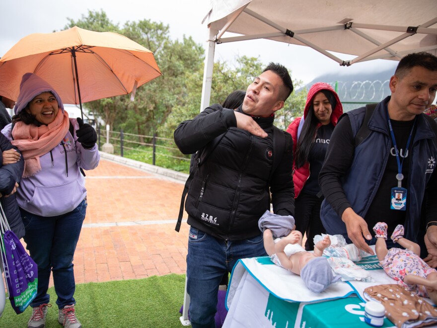 Nelson Alexander Yaguara pretends to wave away the stink of a soiled baby diaper at a pop-up workshop in Bogotá's San Cristóbal neighborhood.