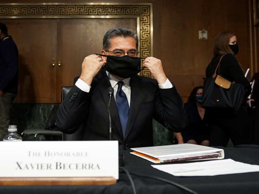 Xavier Becerra, then nominee for secretary of Health and Human Services, puts on his protective mask at his Senate Finance Committee confirmation hearing in February.