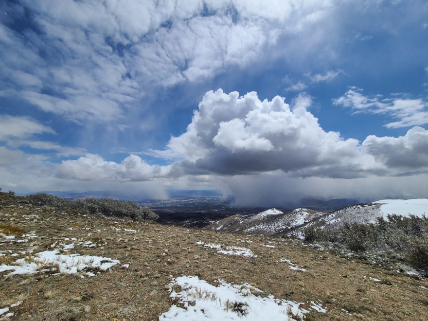 View from on top of a mountain, where it and nearby peaks don't have much snow.