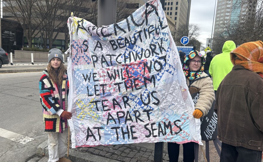 Protestors hold a quilt with a unity message