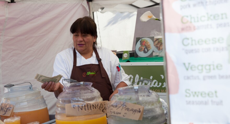 Alicia Villanueva hands change to a customer at a weekly San Francisco street-food market called Off the Grid, where she has a booth selling tamales.