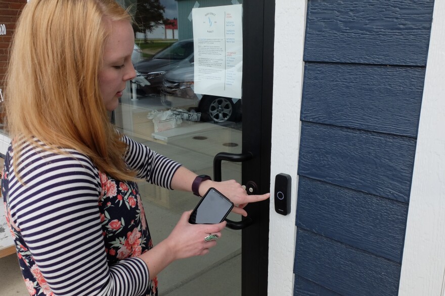 Caileen Ostenson demonstrates the phone app that allows members to open the market any time they want to shop.