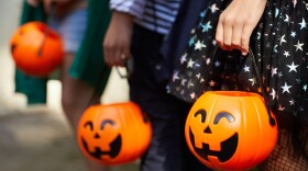 Close-up of children with pumpkins bags playing trick or treat outdoors
