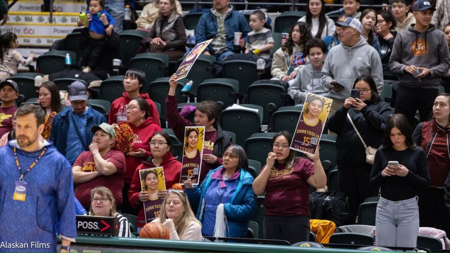 Audience holding up Kelly Hunt's poster at March Madness game