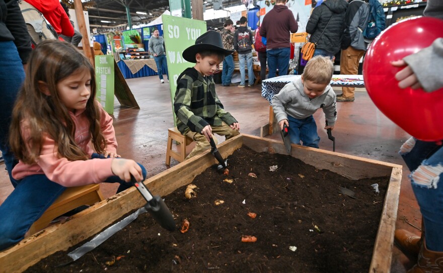 Children dig and rake for root vegetables at a display at the 2025 PA Farm Show.