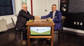 St. Louis Chess Club co-founder Rex Sinquefield (left) shakes hand with Nate Cohen across a "Sinquefield Table."