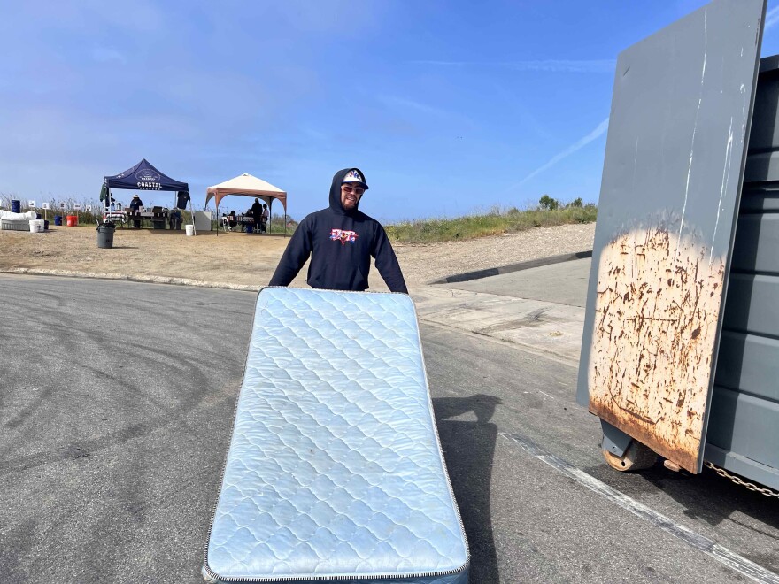 Juan Serrano, a member of Coastal Keepers, tossing a mattress into a garbage container during a clean up event at Ormond Beach in Oxnard in April. Since 2020, Coastal Keepers and other local groups have helped pick up more than 85,000 pounds of trash.