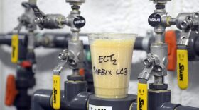 A cup full of gel-based material used to remove PFAS from water sits atop valves that control a groundwater remediation system. PFAS are a group of chemicals, some of which were formerly used in aircraft fire fighting foam. (U.S. Air Force photo by Ty Greenlees)