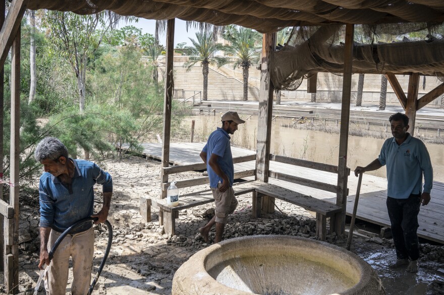Jordanian workers at Jordan's baptism site cleaning up after a recent flood. The marble font is used for baptizing infants who cannot be baptized in the river. The site has been closed to visitors since mid-March due to the coronavirus pandemic and parts of the site have been sterilized.