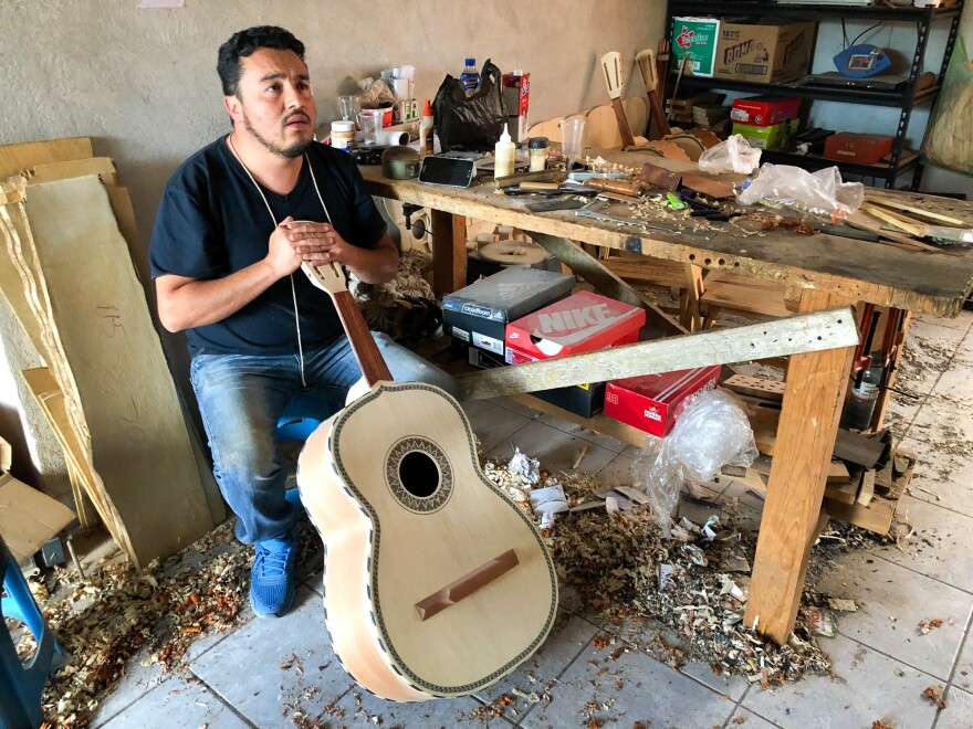 César Ivan Lemus, a third-generation Paracho artisan, shaves the neck of a <em>guitarrón</em> he's making. Lemus sells all types of instruments to mariachi schools and stores in the U.S. He says he's working as fast as he can to keep up with orders these days.