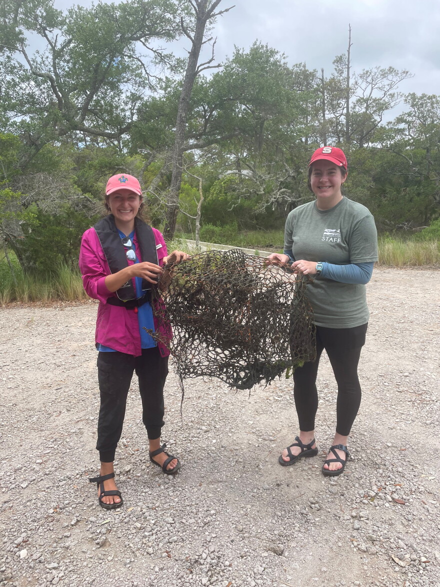 Heather Bariso and Elena Kelly hold up a derelict crab pot which they removed from the waterways around Bald Head Island. The traps are dangerous for diamondback terrapins, who may drown if they get trapped in the abandoned contraptions.