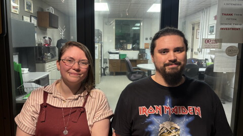A woman and man sitting forward and smiling in a radio studio