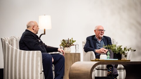 Tom Williams and Corey Flintoff, two older white men, sit on a stage during an audience Q&A.