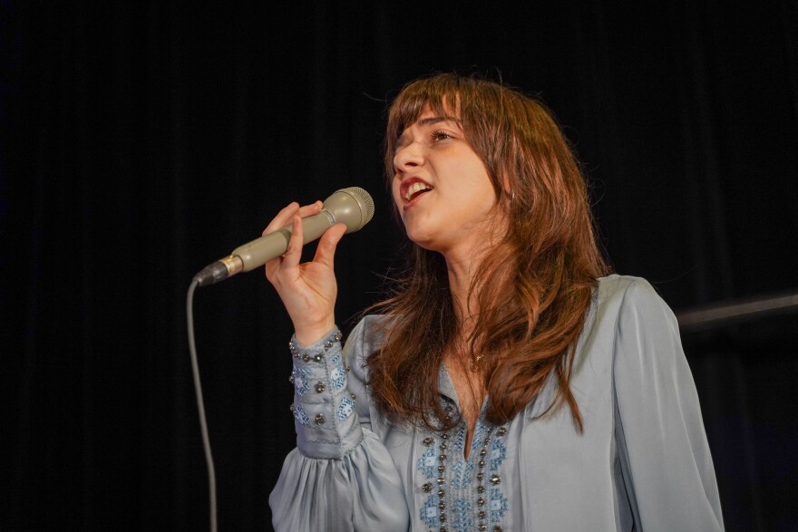 Ava Preston sings in studio holding a microphone