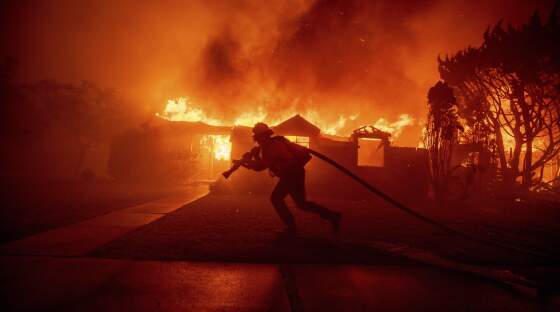 FILE - A firefighter battles the Palisades Fire as it burns a structure in the Pacific Palisades neighborhood of Los Angeles, Jan. 7, 2025.