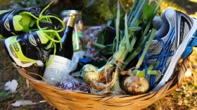  A basket given away to the Buy Nothing community that includes two pairs of running shoes, some fresh vegetables and a bottle of wine among other items.