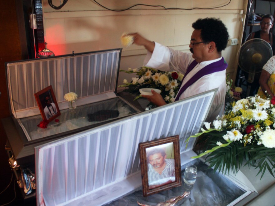 A priest sprinkles holy water on the coffins of photojournalists Gabriel Huge (bottom) and Guillermo Luna during a public Mass in Veracruz last week. Killed by unknown assailants, the bodies were found dumped in plastic bags by a canal in Veracruz less than a week after the killing of Regina Martinez.