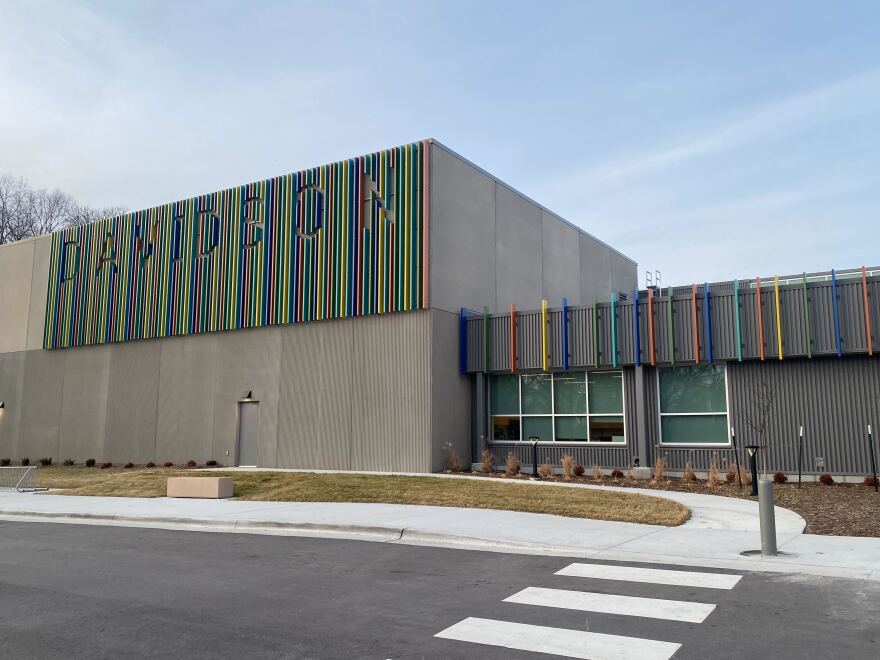 A photo of Davidson Elementary, a concrete school building with rainbow vertical lines on the facade and DAVIDSON spelled out in large letters cut out from the rainbow lines. 