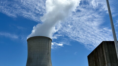A wide shot of the Callaway Nuclear Power Plant cooling tower. It's wider at the top and bottom and white water vapor comes from the top. The sky is light blue with some slim clouds. 