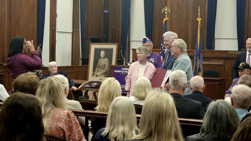 Purple Heart recipient and Army veteran James Burr, grey shirt, receives a certificate from Erie County Clerk Mickey Kearns. Purple Heart recipients from Western New York are added to the William J. Donovan Purple Heart Recipients Book of Merit.