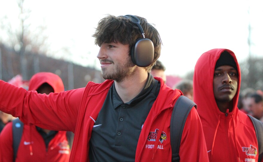 Fans and marching band members greet ISU football players and coaches