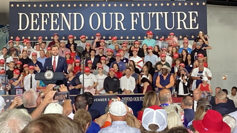 Man speaks at podium in front of a crowd