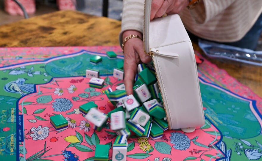 Laurie Gumula pours mah-jongg tiles onto a matching playing mat.