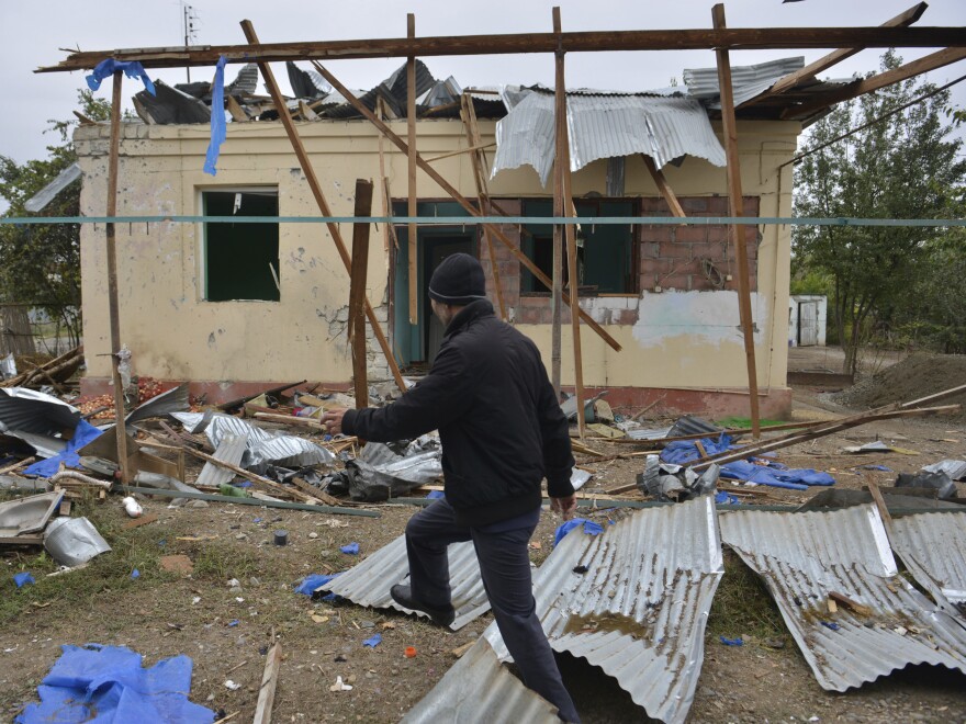 A man walks past a house destroyed by shelling during fighting over Nagorno-Karabakh in Agdam, Azerbaijan, on Oct. 1. The International Committee of the Red Cross says civilian deaths and injuries have been reported.