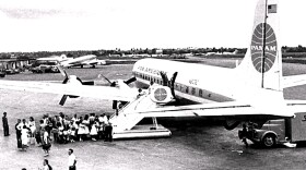 group in BW image gather to get on a Pan Am plane in the 1960s 