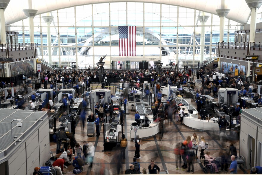 Passengers wait in a security line at Denver International Airport on Feb. 22, 2023. Passengers had to use an emergency slide to evacuate a smoking American Airlines jet at Denver International Airport. The Federal Aviation Administration says the Boeing 737 MAX 8 reported a "possible landing gear incident" during its departure for Miami on Saturday.