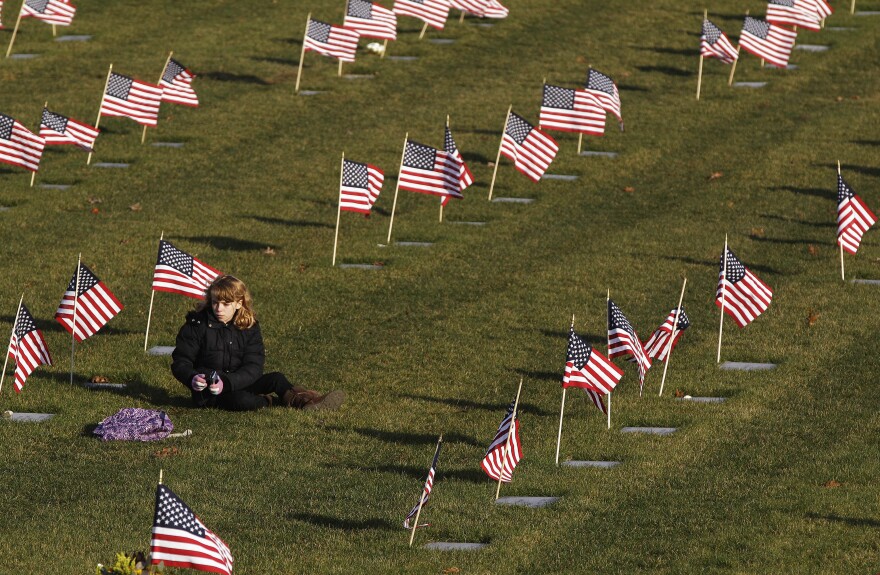 Julia Carpenter, 11, sits at her grandmother's grave, World War II United States Marine Corp veteran Mary Winston, at the National Cemetery in Bourne, Mass., Friday afternoon, Nov. 11, 2011. (AP Photo/Stephan Savoia)